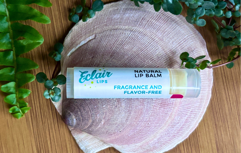 An Eclair Lips Fragrance Free Lip Balm sits atop a shell surrounded by leaves