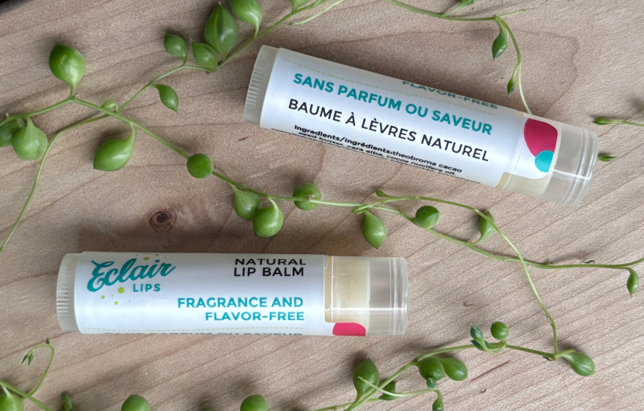 Two tubes of Eclair Lips fragrance free lip balm against a wooden background with plant tendrils around them