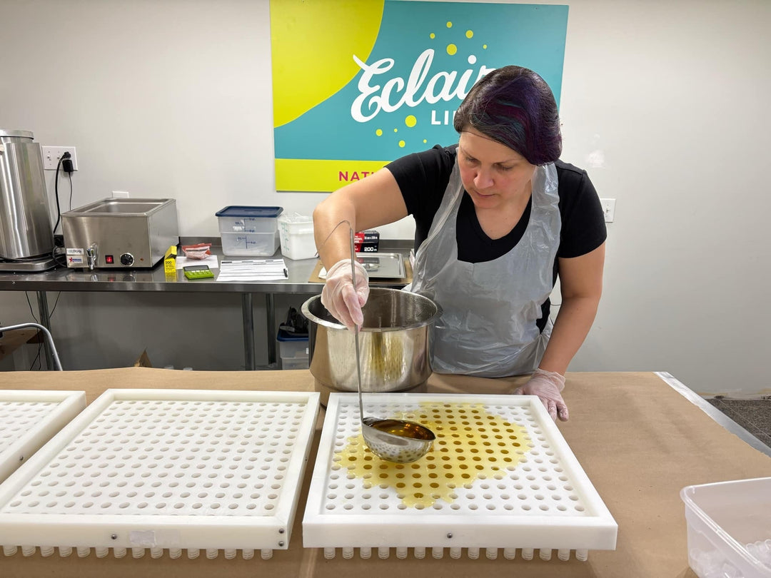 Sylvie, the owner of Eclair Lips pouring melted lip balm into a filling tray with a laddle