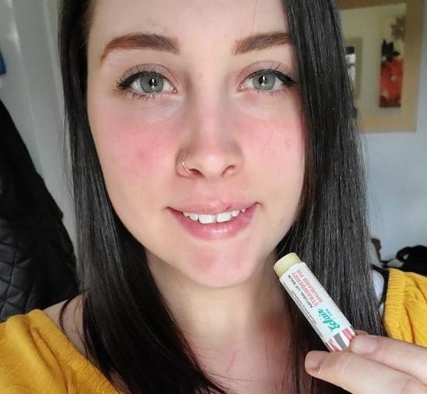 a person applying lip balm to moisturized lips, showing the texture and application of lip care products.