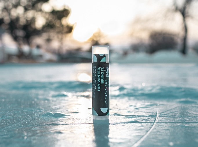 A tube of Eclair Lip Hey Winter Bring It lip balm standing on a frozen lake